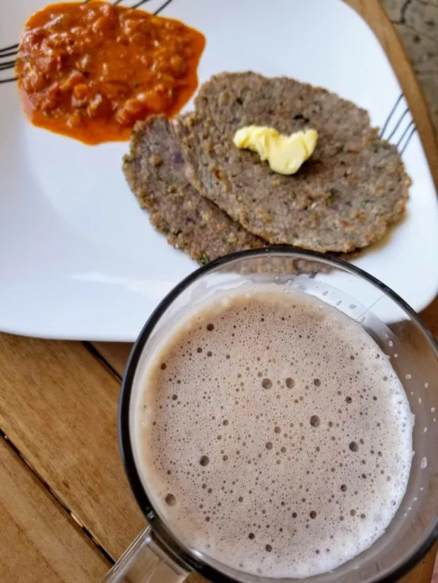 Three millet rotis with a pat of butter and a spoonful of tomato chutney, with a mug of millet malt