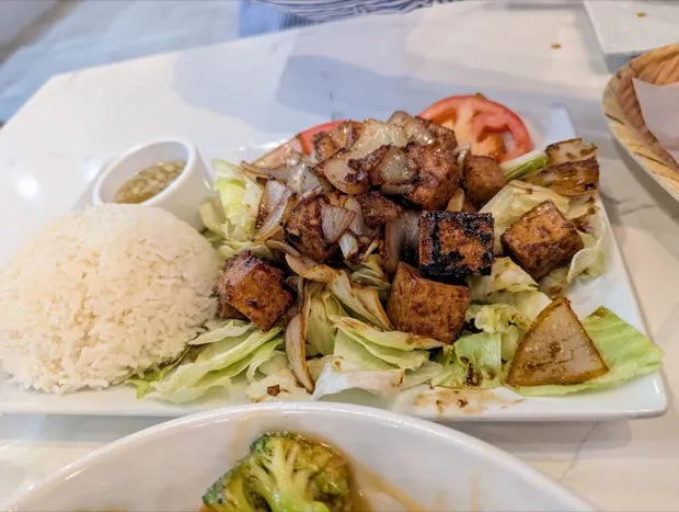 Grilled tofu and onion on shredded lettuce with steamed rice, sliced tomato and a small pot of dipping sauce