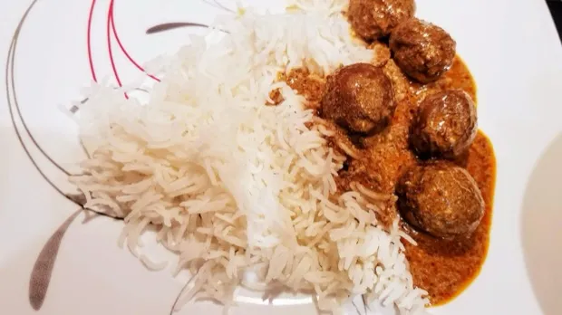 Vegetable koftas in a rich curry beside a mound of steamed basmati rice