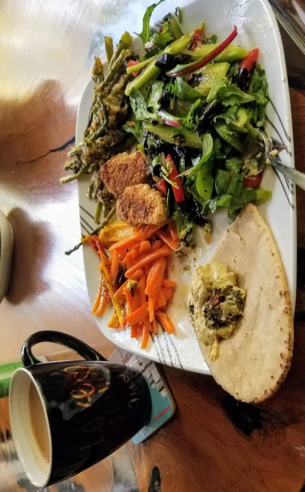 A leaf salad with crumb-coated cutlets, sautéed green beans, carrot batons and a flatbread spread with green curry