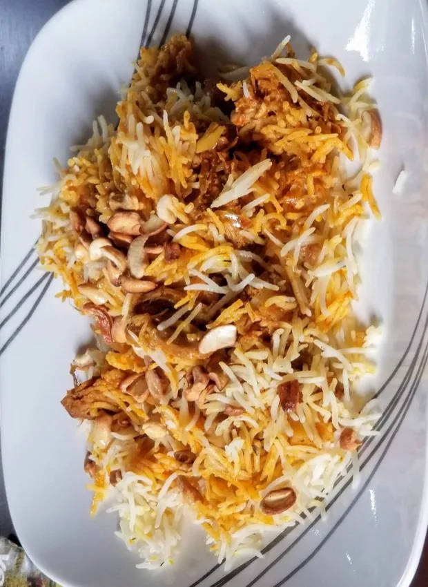 Vegetable biryani on an oval platter, scattered with cashews and fried onion