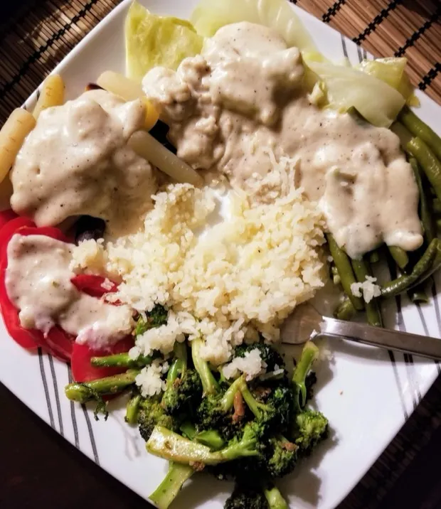 Steamed rice with cabbage, green beans, red pepper and roasted broccoli under a creamy white sauce