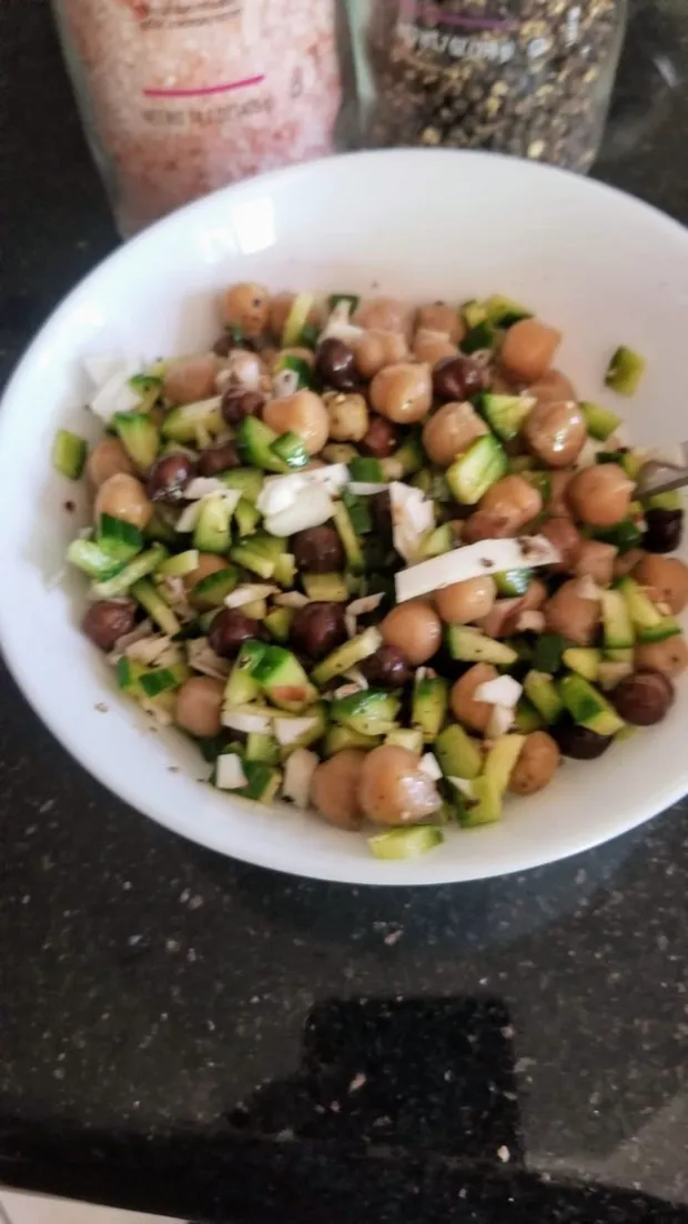 A bowl of chickpeas and black chana tossed with diced cucumber and onion