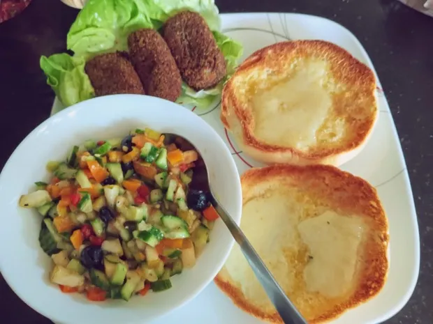 A bowl of finely diced pepper, cucumber, apple and olive salad, with lettuce-lined croquettes and toasted buns