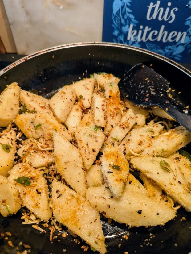 Idli wedges tossed in a pan with cumin, sesame, chilli powder and curry leaves