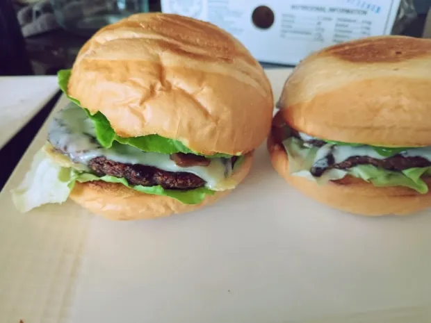 Two vegetable burgers in soft buns with melted cheese and lettuce